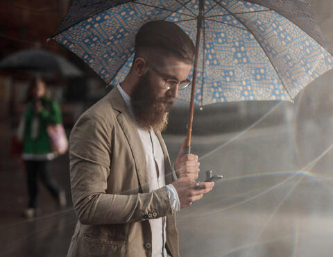 Man using phone while holding an umbrella