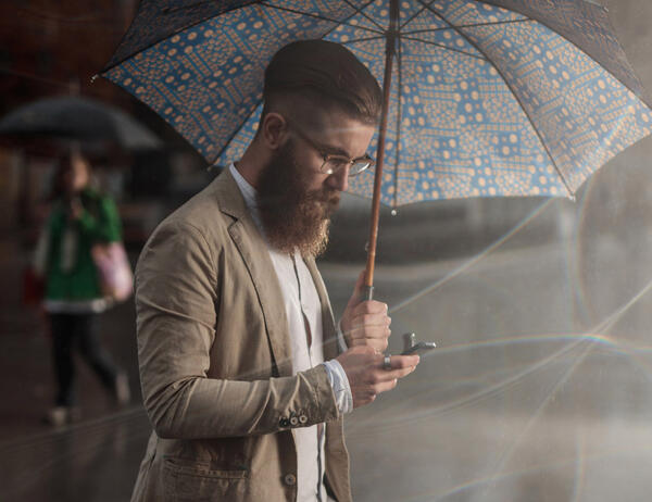 Man using phone while holding an umbrella